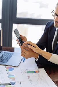 man in black suit holding a black smartphone